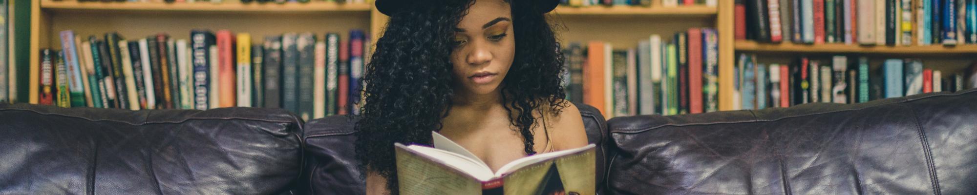 Young woman in a hat reading in a library.